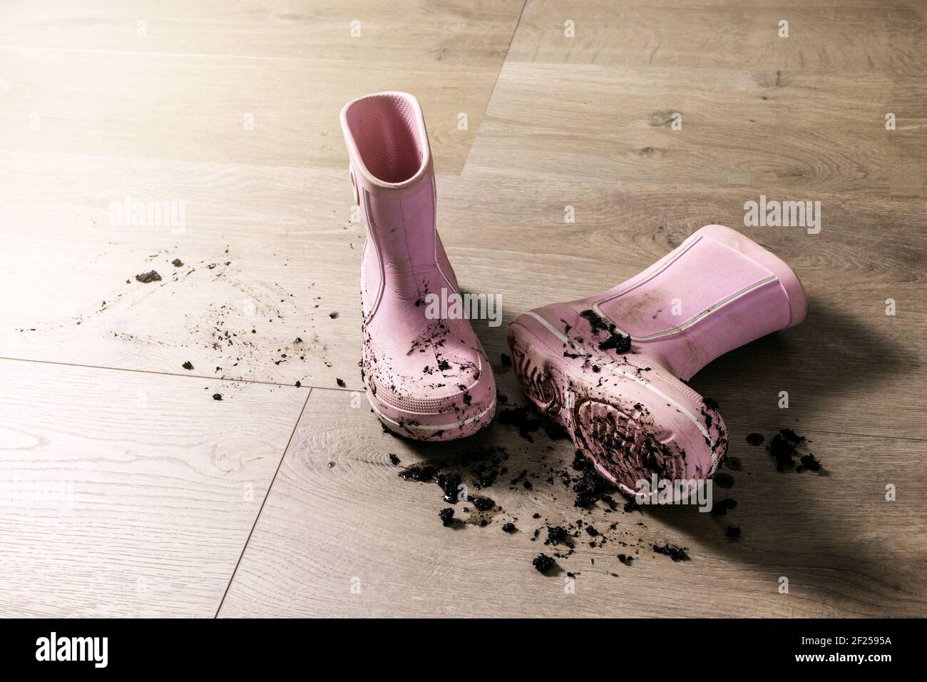 Schmutzige schlammige Kinder Gummi Regen Stiefel auf Laminatboden Stockfoto