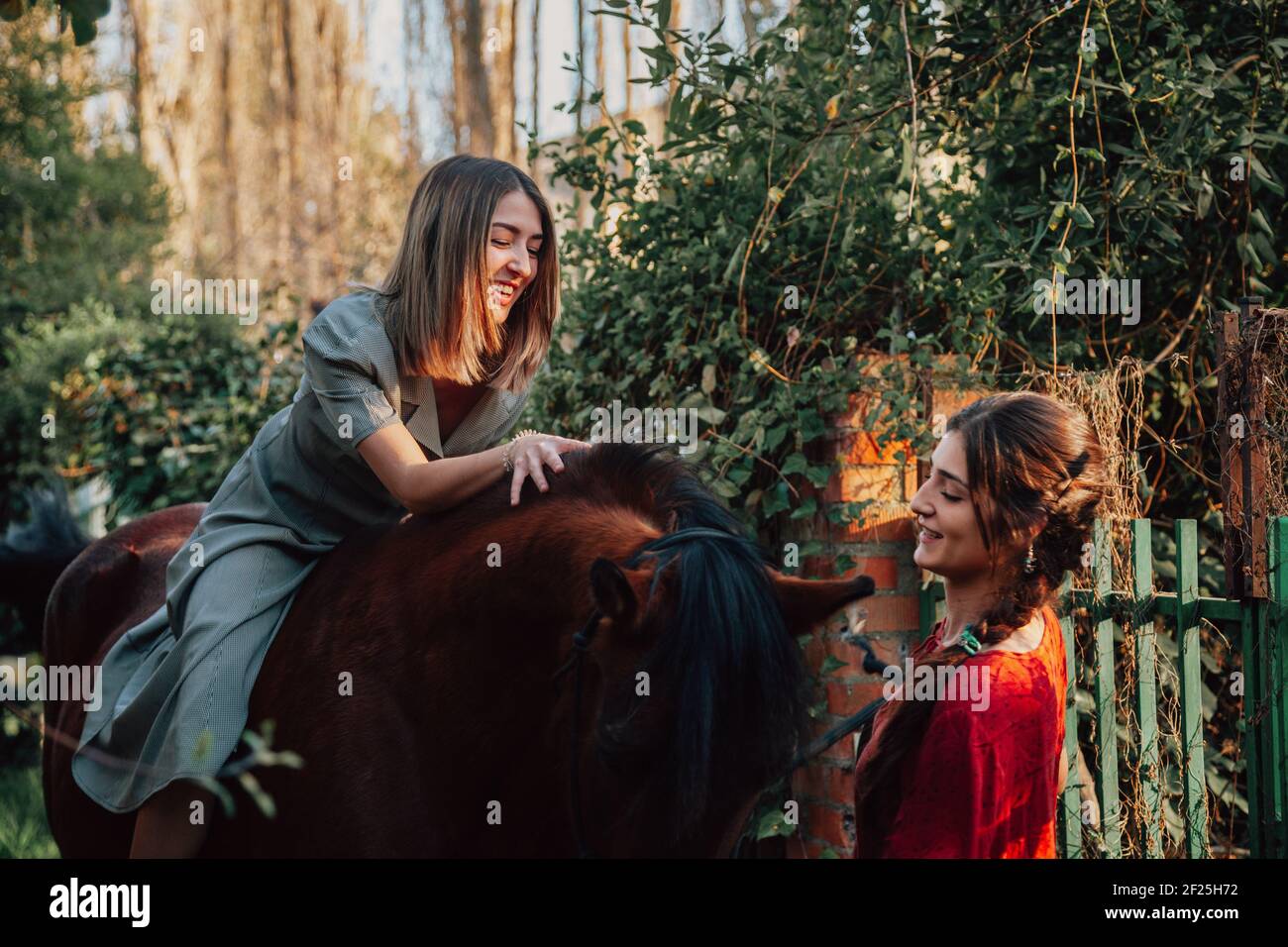 Zwei Freundinnen plaudern und reiten mit ihren Reiten Sie durch die Landschaft Stockfoto