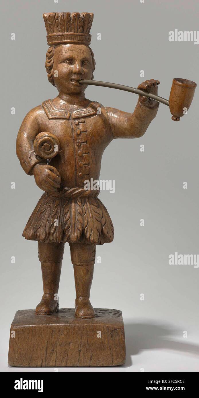 indischer Tabak. Stoppfigur mit einem losen Rohr (NG-2007-64-1) in der linken Hand und einer Rolle in der rechten Hand (Tabak, bevor sie sich drehen). Der Mann trägt eine auffällige Kombination aus (angeblicher) einheimischer und westlicher Predigt: Einen Transit, einen Rock aus Tabakblättern, einen westlichen Yak mit Knoten und westliche Lederstiefel mit Deckel. In der Linken liebte er ein Objekt, das verloren gegangen ist. Das Bild befindet sich auf einer Basis, die zusammen mit dem Bild aus einem Stück Holz geschnitten wurde. Werbemittel für den Tabakhandel oder -Verkauf. Stockfoto