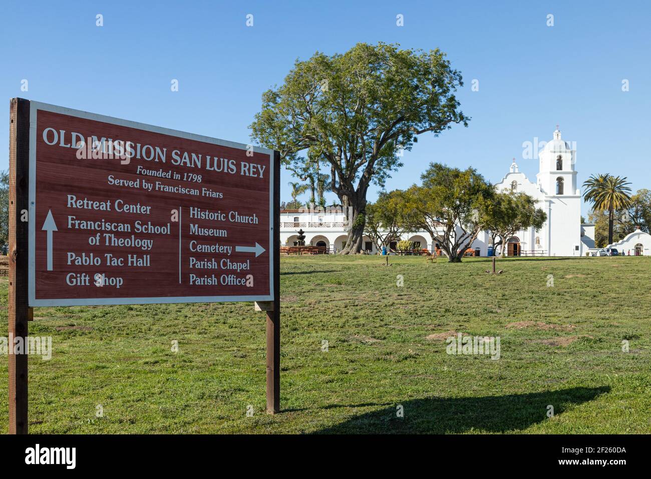 Oceanside, California USA - 5. März 2021: Eingangsschild mit Wegweiser zur Old Mission San Luis Rey, Kirche und Gebäuden im Hintergrund Stockfoto