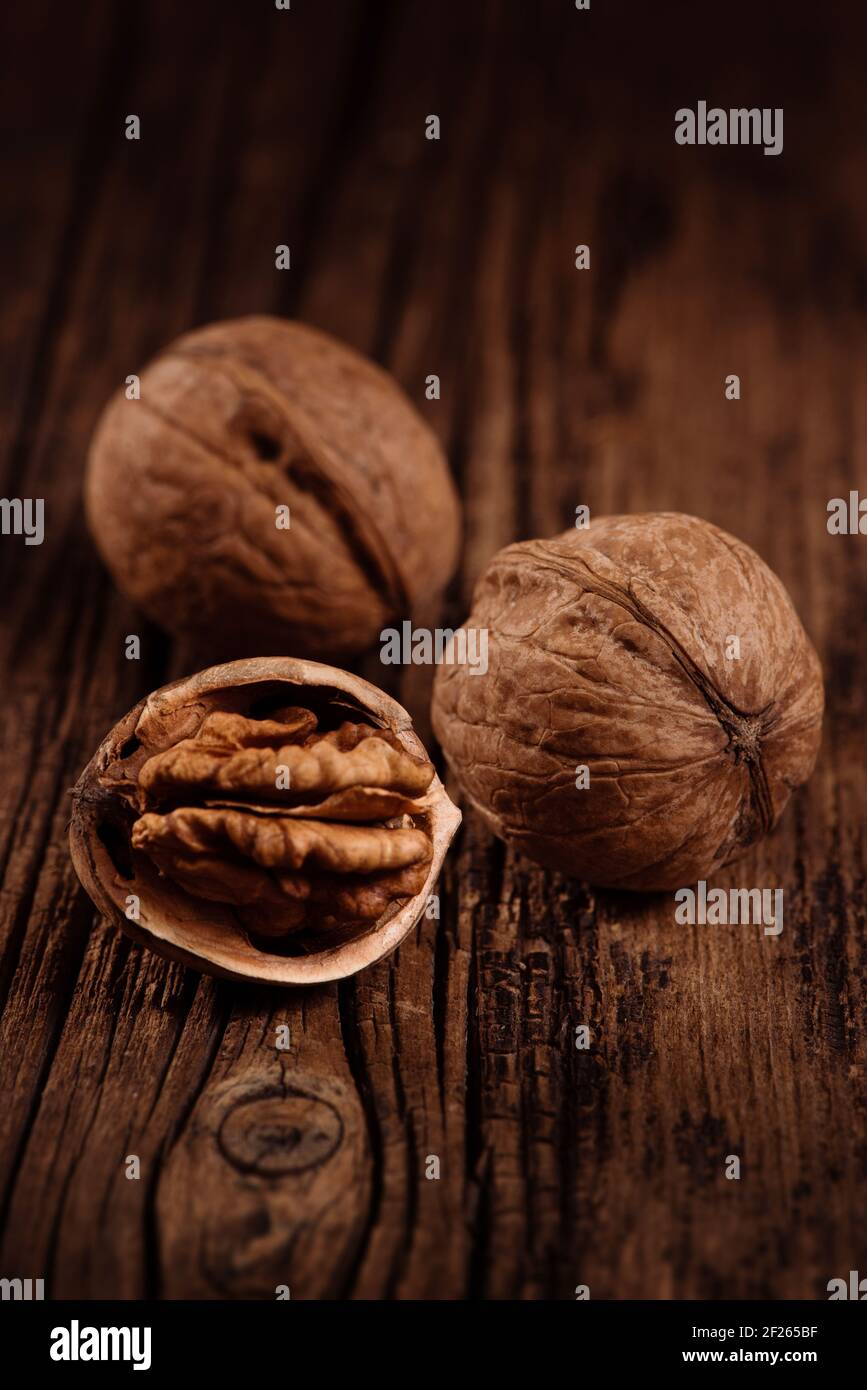 Drei reife Walnüsse auf strukturiertem Holz braun Hintergrund. Nahaufnahme. Selektiver Fokus Stockfoto