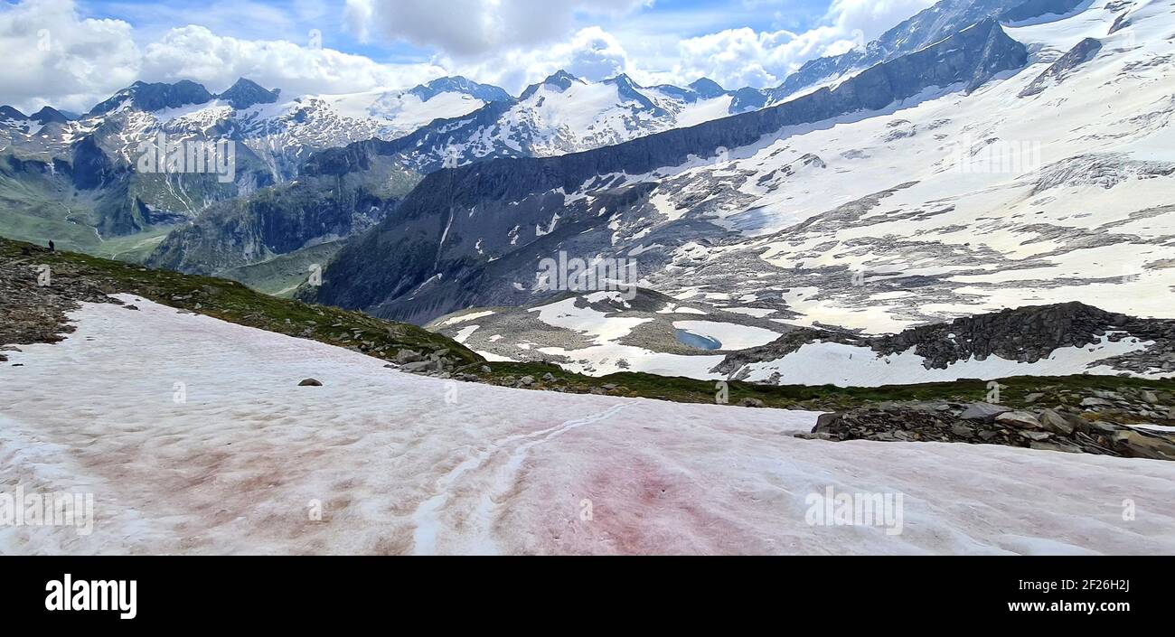 Weite Sicht auf die Berliner Hütte mit leicht rosa Schnee Im Vordergrund und schneebedeckte Berge und alpine Teiche Im Hintergrund Stockfoto