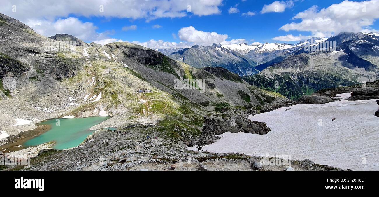 Panoramablick auf die Friesenberghaus Hütte und einen türkisfarbenen See mit einer Kulisse von schneebedeckten Zillertaler Alpen im Juni, Österreich Stockfoto