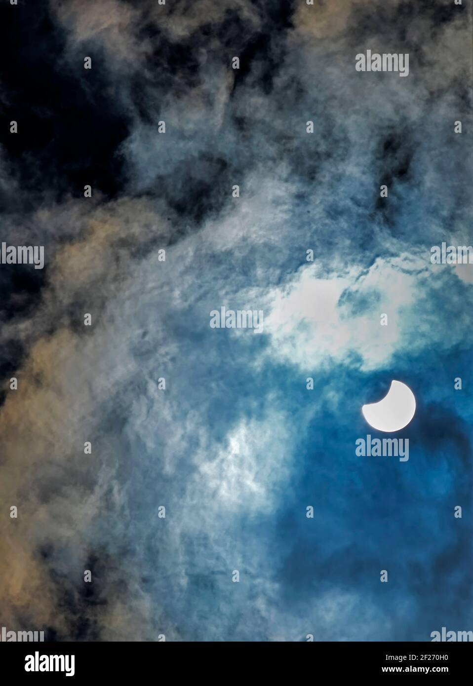 Partielle Sonnenfinsternis durch Wolken betrachtet Stockfoto