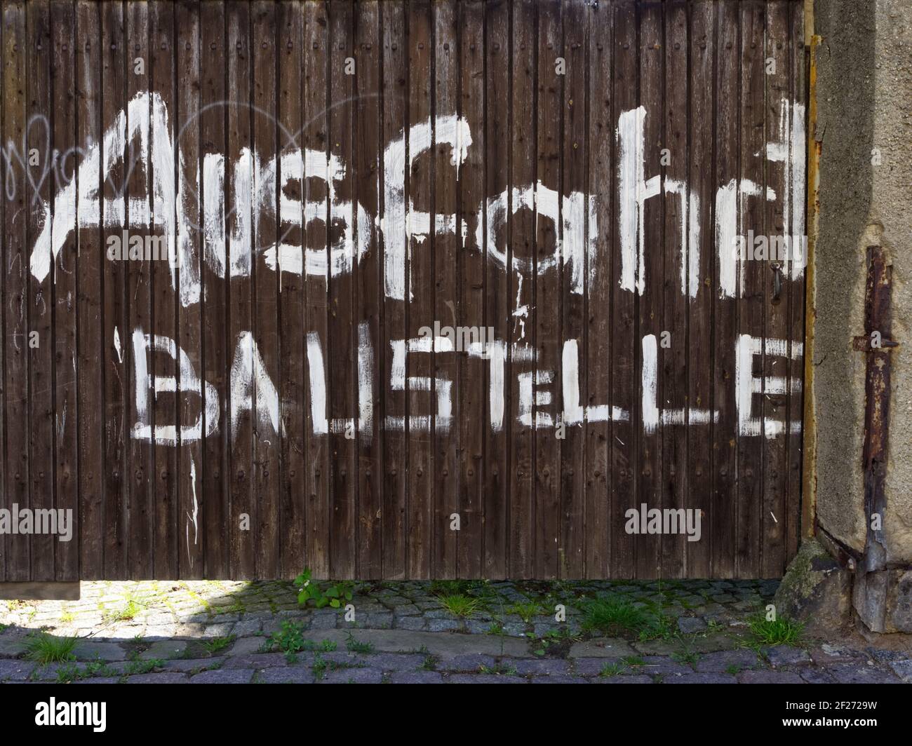 Großes Tor mit deutscher Aufschrift 'Exit Construction site'. Holztür mit großer Schrift. Tor mit weißer deutscher Aufschrift 'Ausfahrt Baustelle'. Stockfoto