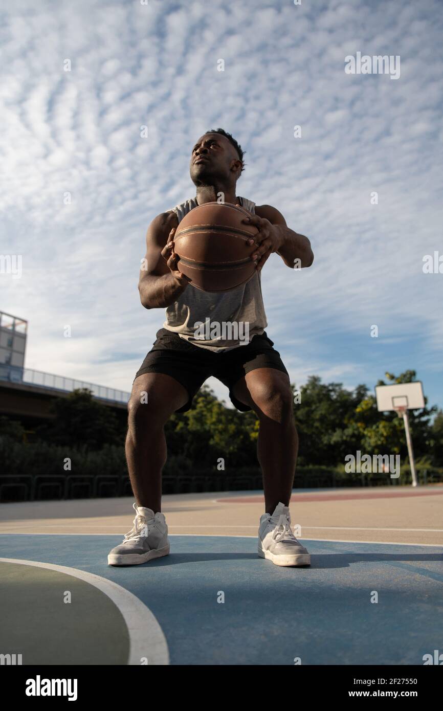 Schwarzer Basketballspieler hockt vor dem Wurf Stockfoto