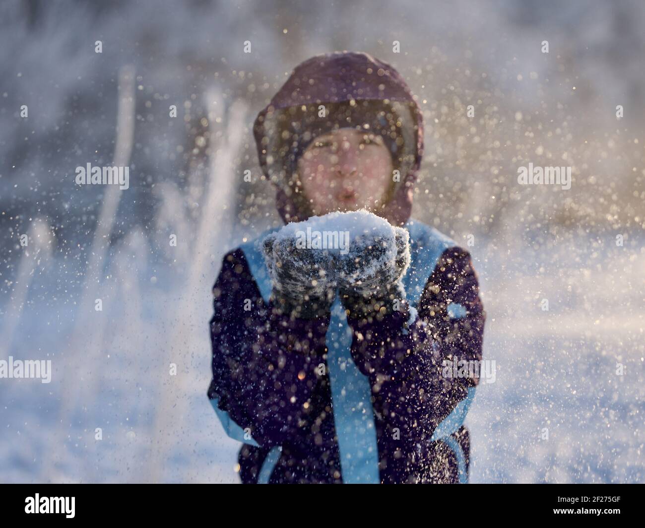 Portrait von Mädchen weht Schneeflocken zur Kamera im Winter, konzentrieren sich auf Schnee Stockfoto