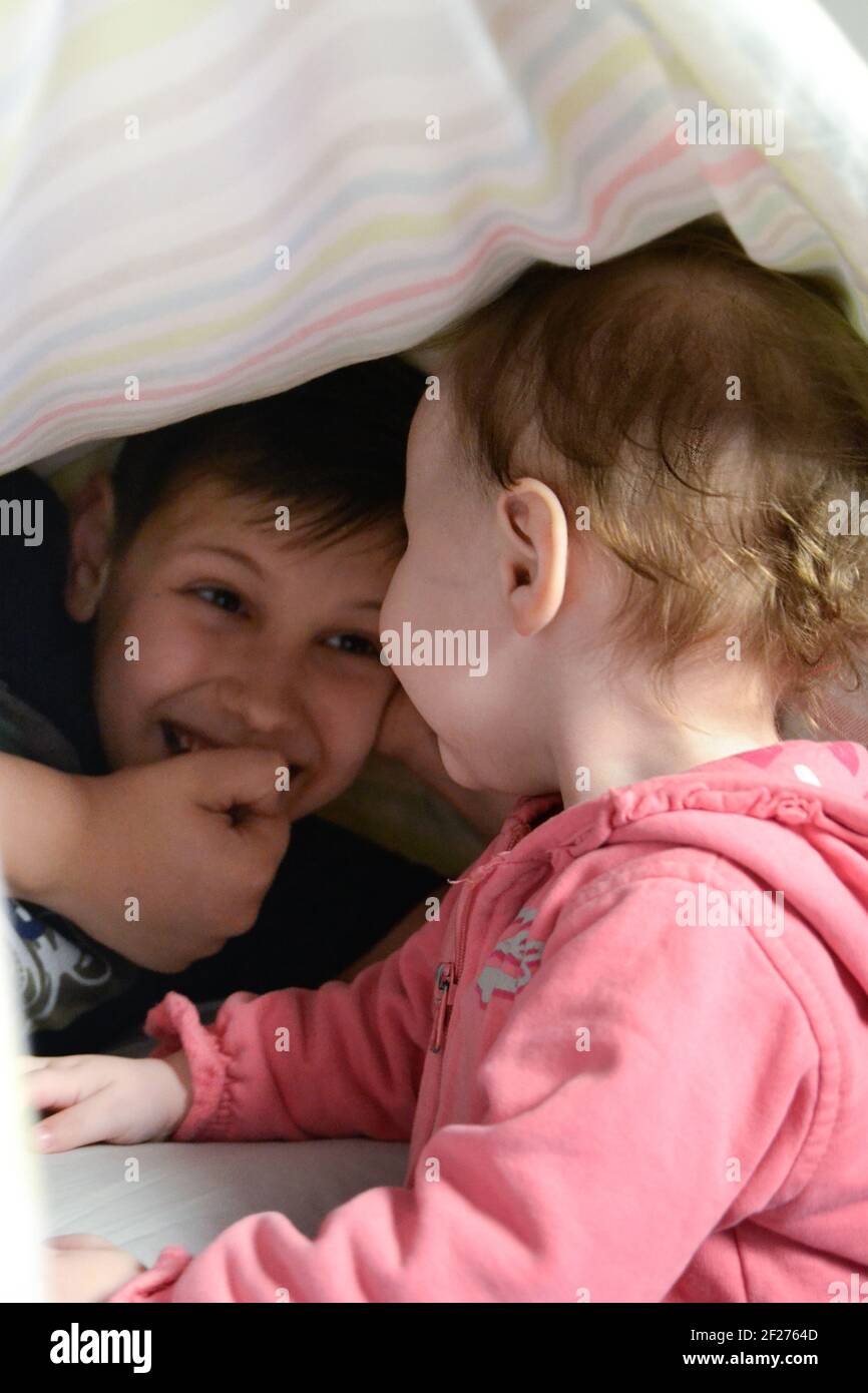 Baby sah ihren Bruder an, der sich unter der Decke versteckte Stockfoto