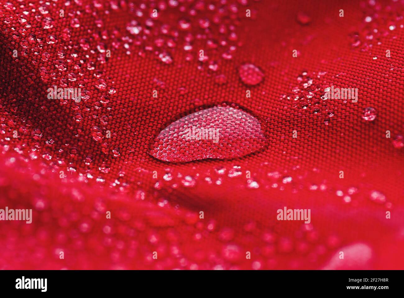 Großer Wassertropfen auf rotem wasserdichtem Stoff Stockfoto