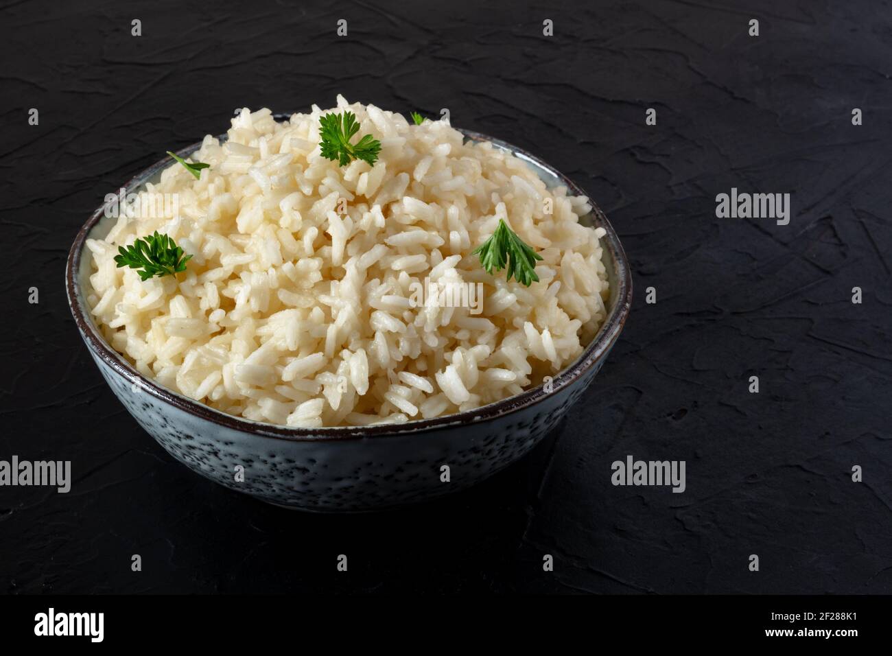 Eine Schüssel mit weißem Langkornreis auf einem schwarzen Hintergrund Stockfoto