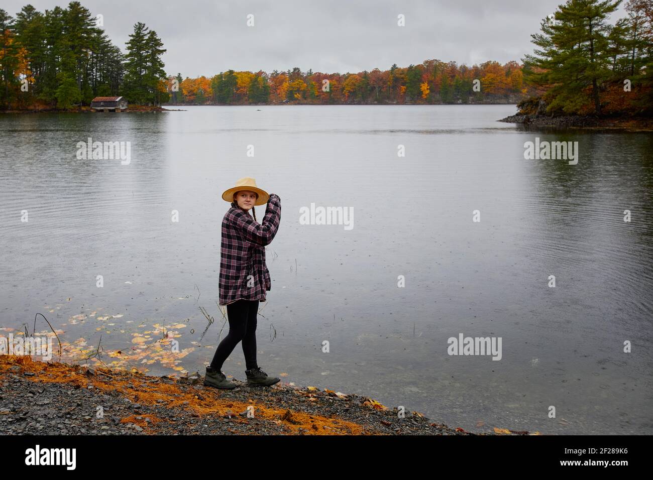 Junge Frau, die an einem regnerischen, bewölkten Nachmittag an einem See in Ontario steht. Stockfoto