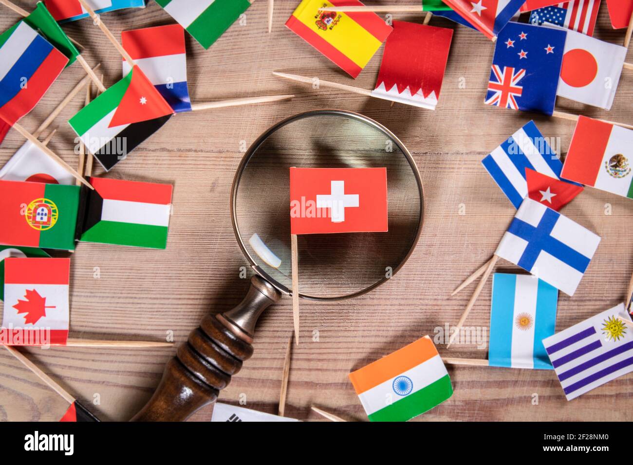 Schweizer Flagge. Wirtschaftswachstum, Import und Export, Rüstungs- und Sicherheitskonzept. Lupe und Flaggen verschiedener Länder. Stockfoto