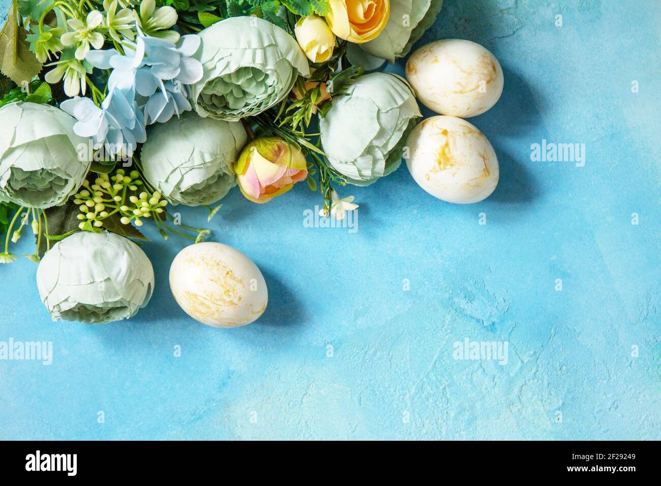 Frohe Ostern Hintergrund. Frühlingsblumen und Ostereier auf einem betonblauen Hintergrund. Draufsicht flach liegend. Speicherplatz kopieren. Stockfoto