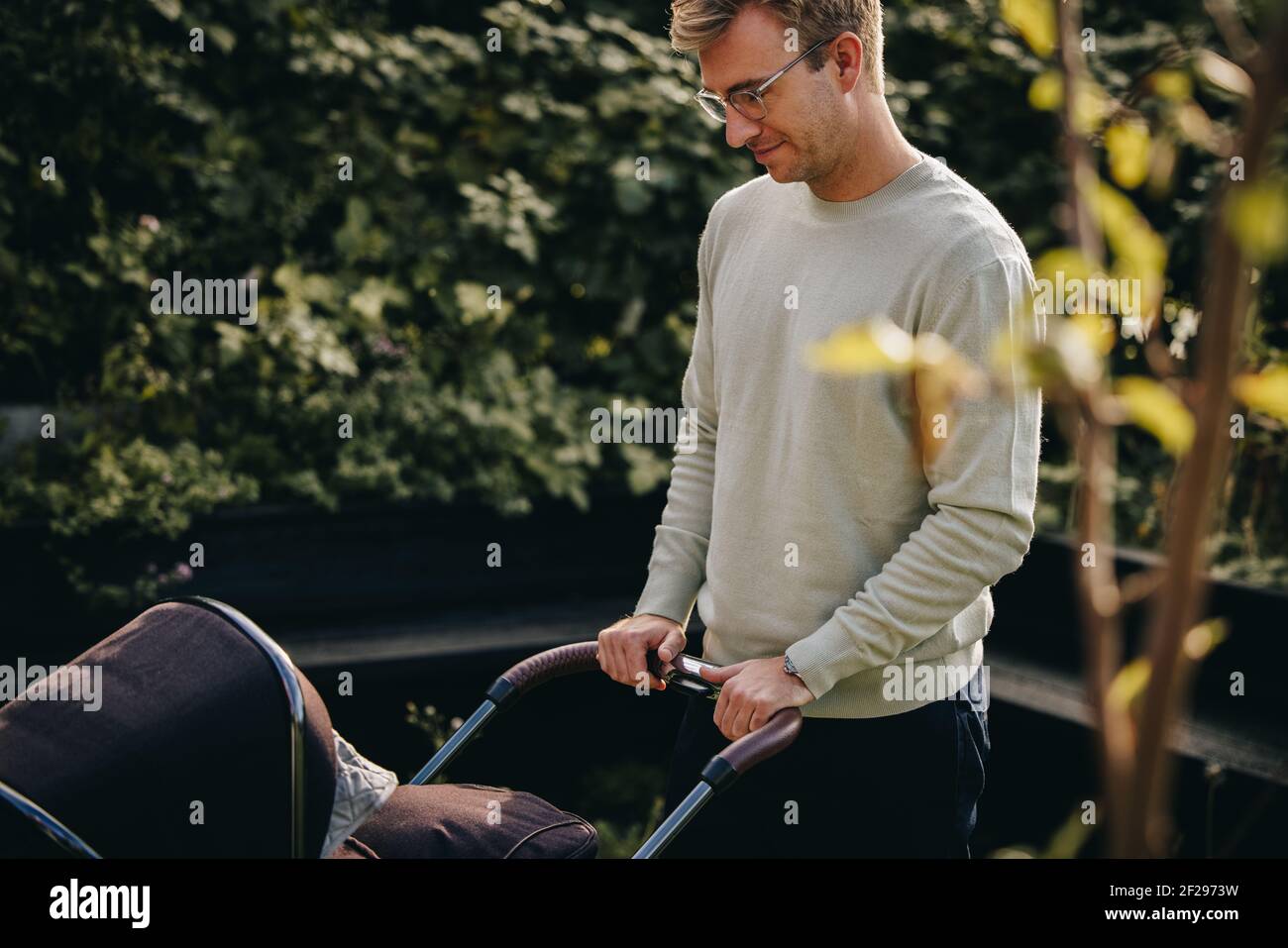 Mann, der den Kinderwagen nach draußen schiebt. Vater mit Baby im Kinderwagen. Stockfoto