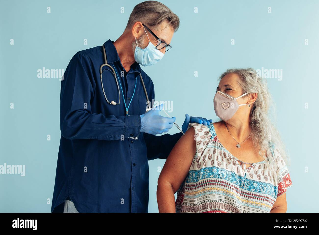 Ältere Frau erhält zweite Coronavirus-Impfdosis für volle Immunität. Arzt, der während einer Pandemie eine ältere Frau mit Gesichtsmaske impft. Stockfoto