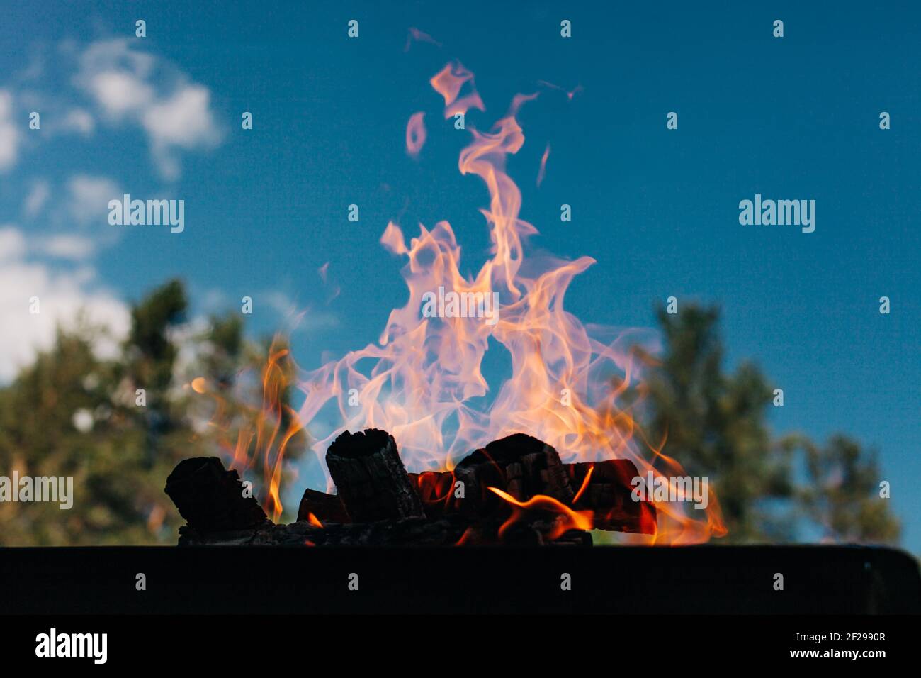 Lagerfeuer draußen, orange Flammen auf blauem skye Stockfoto