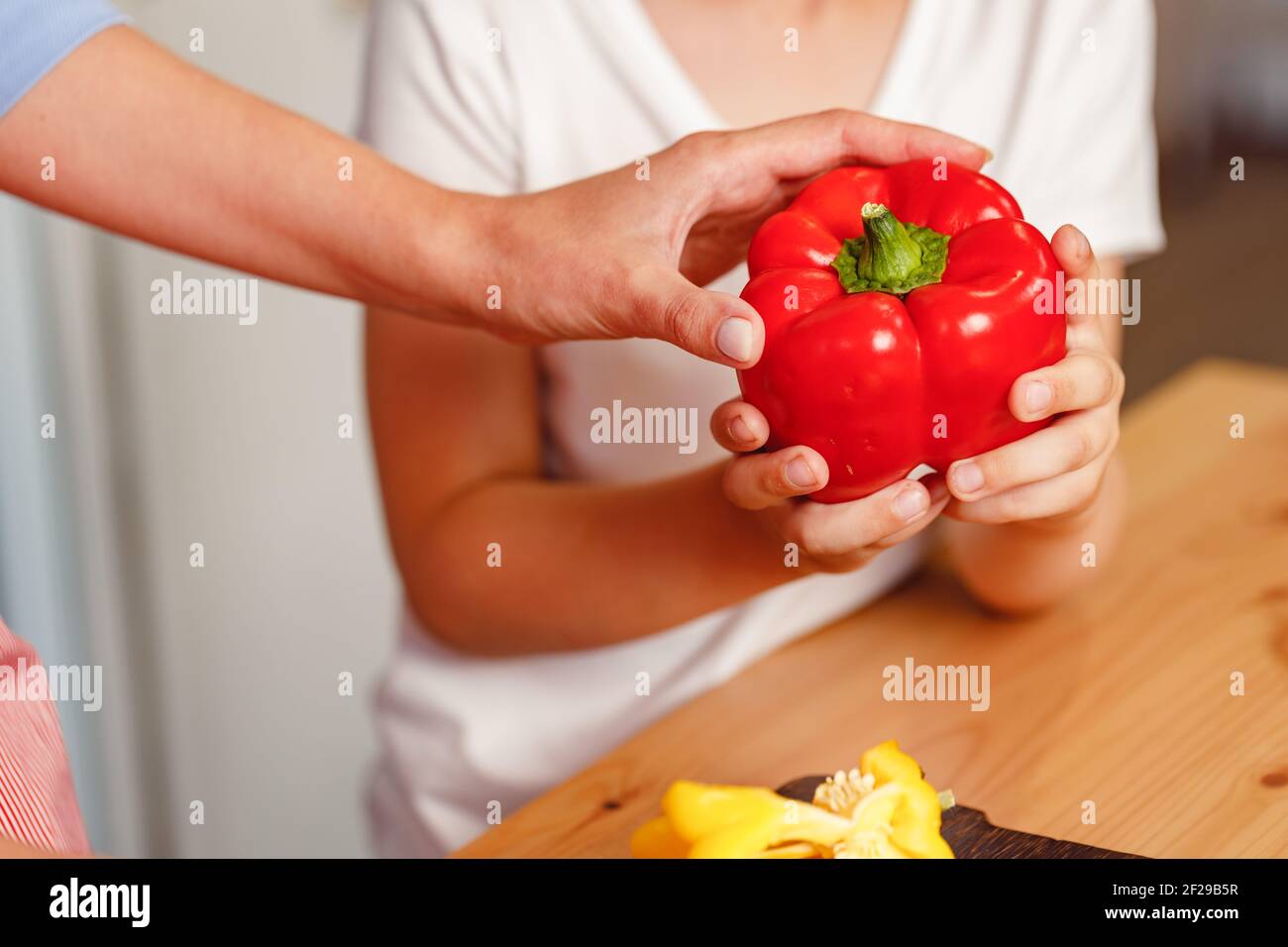 Weibliche Hand hält Paprika über dem Tisch Stockfoto