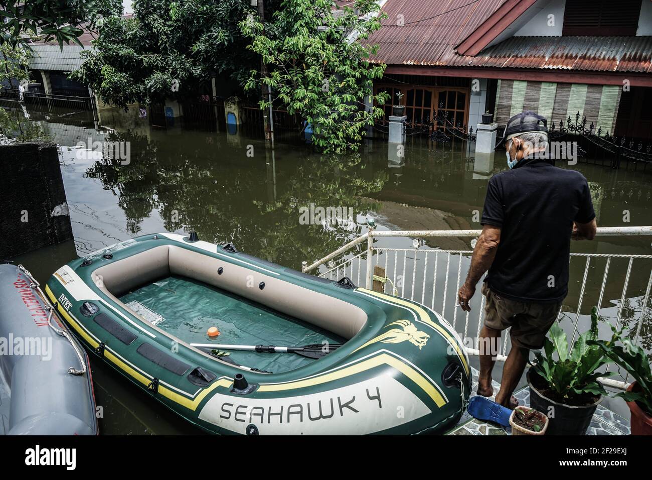 Makassar, Süd-Sulawesi, Indonesien. März 2021, 11th. Ein Mann bereitet ein aufblasbares Boot vor, um ein überflutungsgebeuteltes Gehäuse zu überqueren. Überschwemmungen ereigneten sich in der Stadt Makassar und führten dazu, dass Dutzende von Häusern in Wasser getaucht wurden, so dass die Bewohner an einen sicheren Ort evakuiert werden mussten. Quelle: Herwin Bahar/ZUMA Wire/Alamy Live News Stockfoto