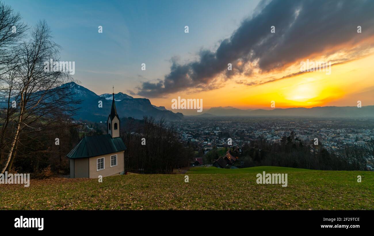 Schöner Sonnenuntergang und Nachglühen in Dornbirn mit Wolken, die auf die Rhomberkapelle zeigen, farbiger Himmel über Rheintal, Staufenspitze, Säntis Stockfoto