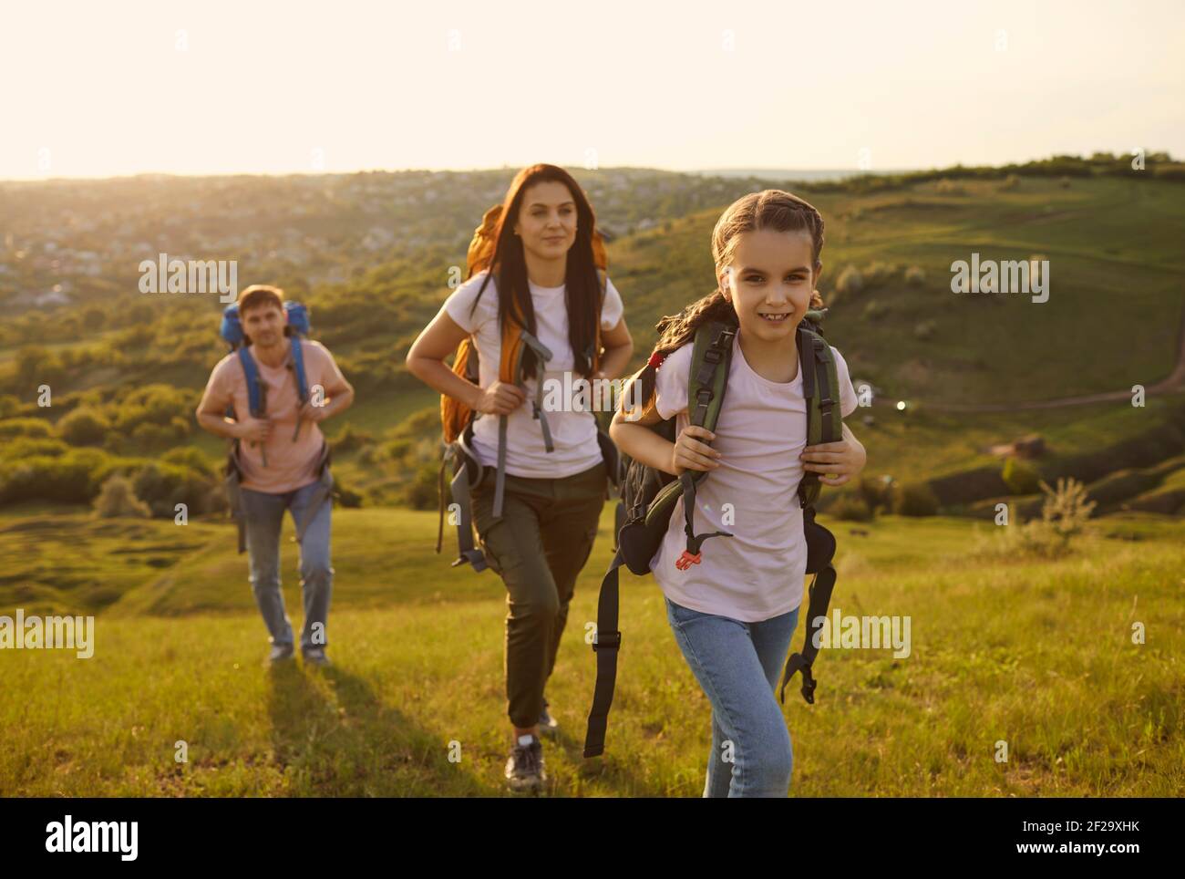 Familie mit Rucksäcken auf touristische Reise in den Bergen. Nettes Mädchen mit Eltern Camping in der Wildnis während der Sommerferien Stockfoto