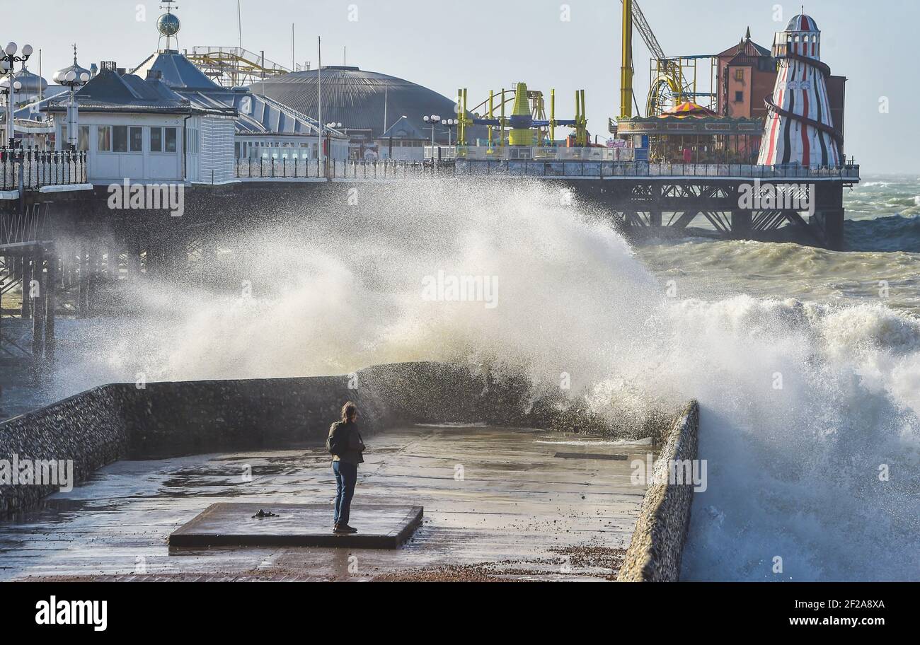 Brighton UK 11th March 2021 - EIN Fotograf fängt die Wellen, die am Pier an der Küste von Brighton krachen, ein, während stürmisches Wetter heute die Südküste schlägt : Credit Simon Dack / Alamy Live News Stockfoto