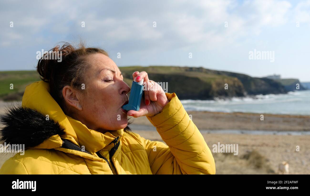 Reife Frau mit einem Inhalator an einem Strand Lage - John Gollop Stockfoto