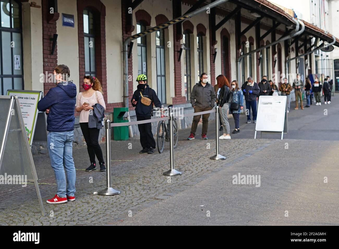 Prag, Tschechische Republik - April 15 2020: Coronavirus Covid-19 Sicherheitsabstand, Menschen warten in einer langen Schlange vor dem Geschäft mit elektronischen Stockfoto