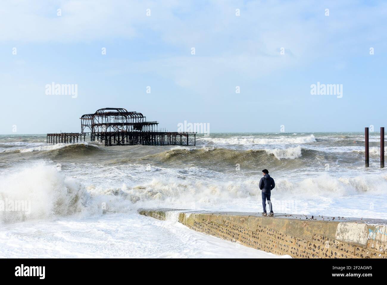 Brighton & Hove, Großbritannien. MÄRZ 11th 2021. Ein Mann sieht aus einer Groyne, wie Brighton's alter West Pier den Sturm verwittert, während riesige Wellen und starke Winde die Südküste schlagen. Foto ©Julia Claxton Credit: Julia Claxton/Alamy Live News Stockfoto