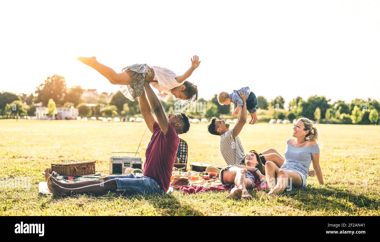 Junge multirassische Familien mit Spaß spielen mit Kindern bei pic nic Grillparty - multikulturelle Freude und Liebe Konzept mit Gemischte Rasse Menschen zusammen Stockfoto