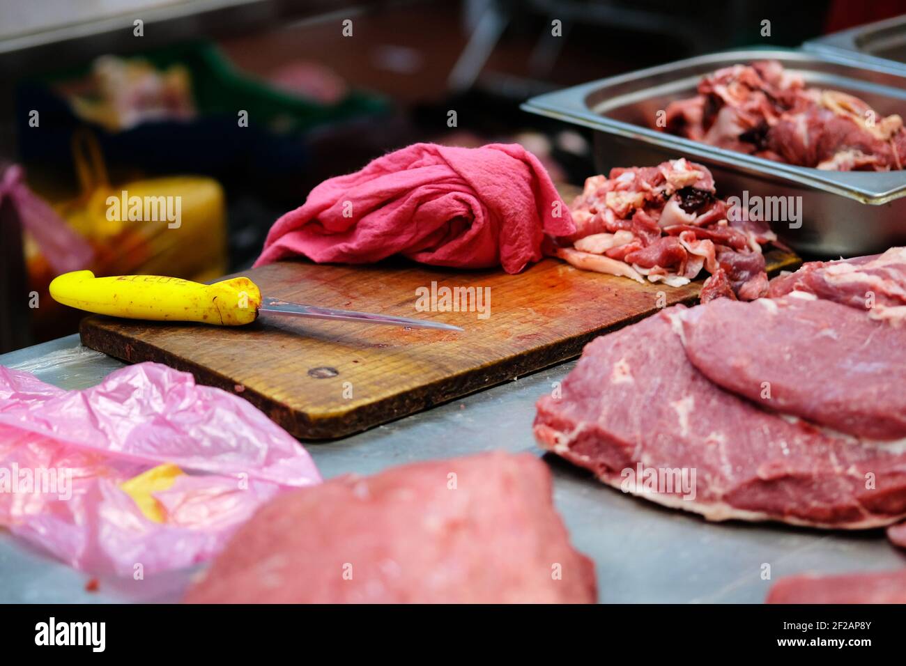 Theke des Verkäufers von frischem Fleisch auf dem lokalen Bauernmarkt. Holzschneidebrett, Messer, roter Lappen, Schweinefleisch, Rindfleisch, Behälter mit Fetzen. Stockfoto