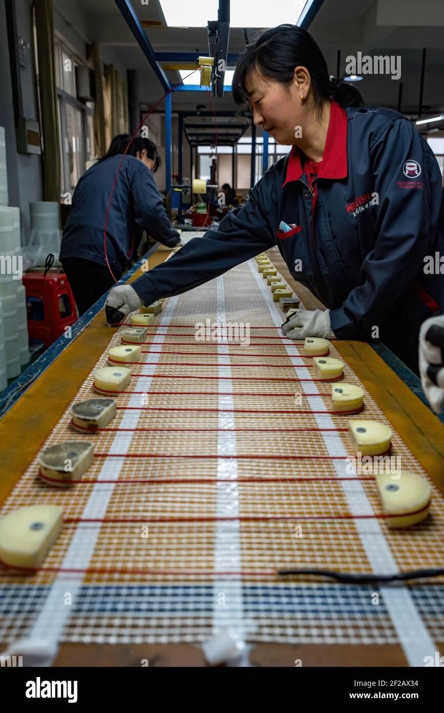 HEFEI, CHINA - 11. MÄRZ 2021 - die Arbeiter produzieren die fertigen  Produkte und Zubehör der elektrischen Heizung Bodensaugung für den Export  in einige europäische Länder in einer Werkstatt in Hefei, Provinz