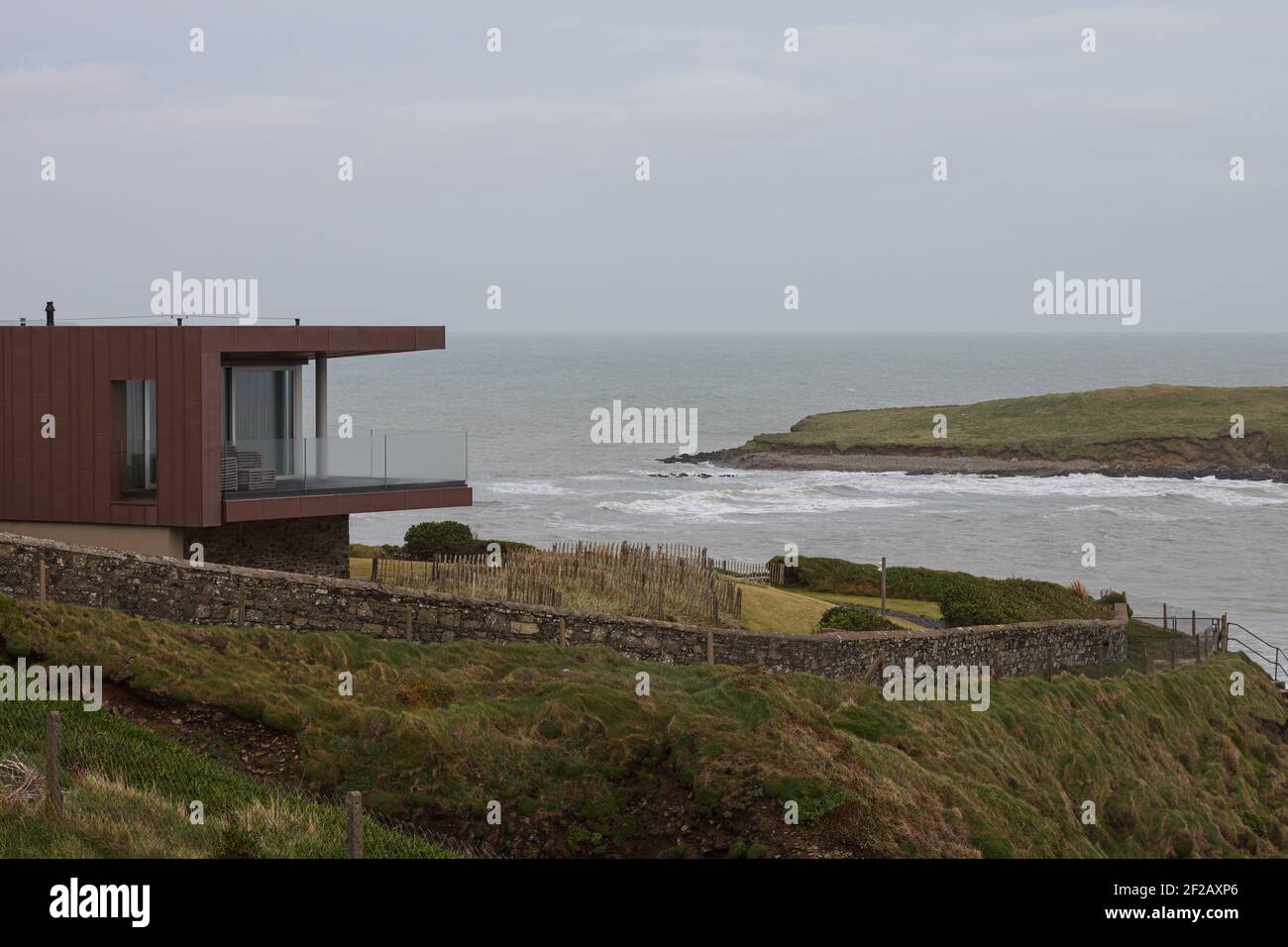 Modernes Haus am Rande der Klippe in Irland mit Blick auf kleine Insel am Atlantik, moderne Architektur, Glas und Stahl, am Rande Stockfoto