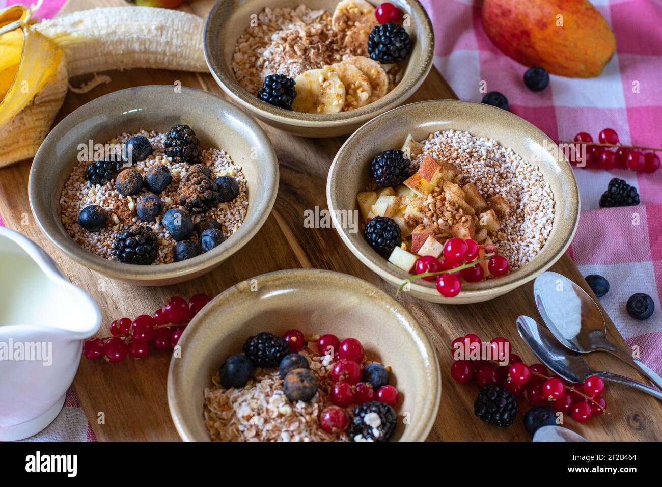 Stillleben von Familienfrühstück mit Haferflocken, Müsli, Müsli und Müsli gekrönt mit Obst und Nüssen und serviert in rustikalen Schalen Stockfoto