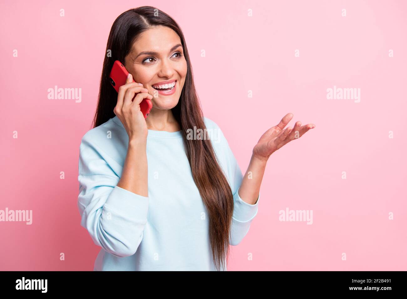 Foto-Porträt von Brünette sprechen auf Handy gestikulierenden Händen Blick auf leeren Raum isoliert auf pastellrosa Hintergrund Stockfoto