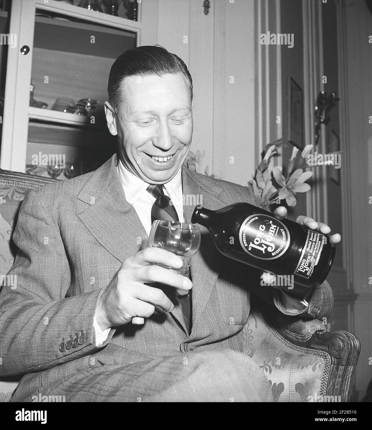 George Formby. Britische Sängerin, Schauspieler als Ukulele-Mann bekannt. 1904-1961. Er war der am höchsten bezahlte britische Schauspieler 1940. Hier abgebildet, als er Stockholm besucht Schweden Gießen sich ein Glas Long John Scotch Whisky. 1946 Ref. T137-4 Stockfoto