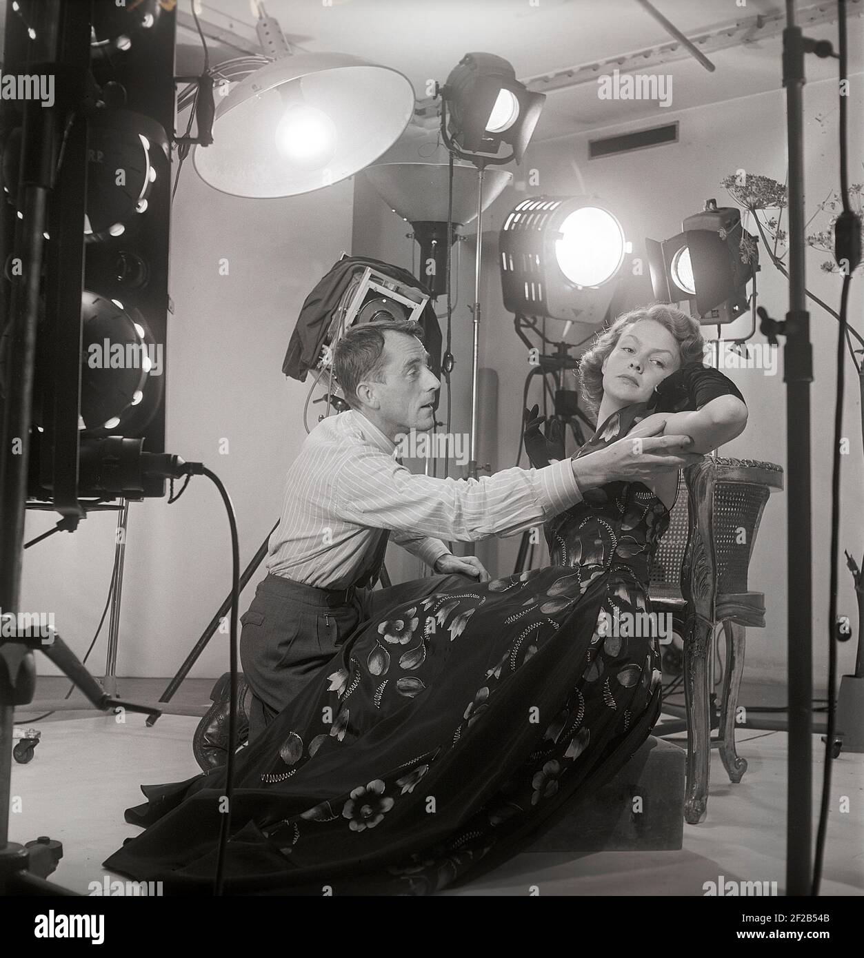 1940s Modefotograf und Model. Eine junge weibliche Modell ist in einem Fotografen Studio einige letzte Anweisungen vor der Aufnahme der Bilder gegeben. Lampen und die Kamera ist sichtbar. Schweden 1949 Ref. AT7-6 Stockfoto