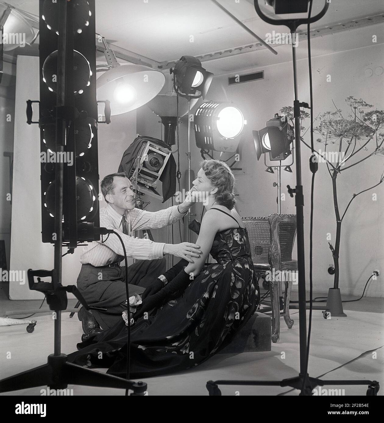 1940s Modefotograf und Model. Eine junge weibliche Modell ist in einem Fotografen Studio einige letzte Anweisungen vor der Aufnahme der Bilder gegeben. Lampen und die Kamera ist sichtbar. Schweden 1949 Ref. AT7-7 Stockfoto