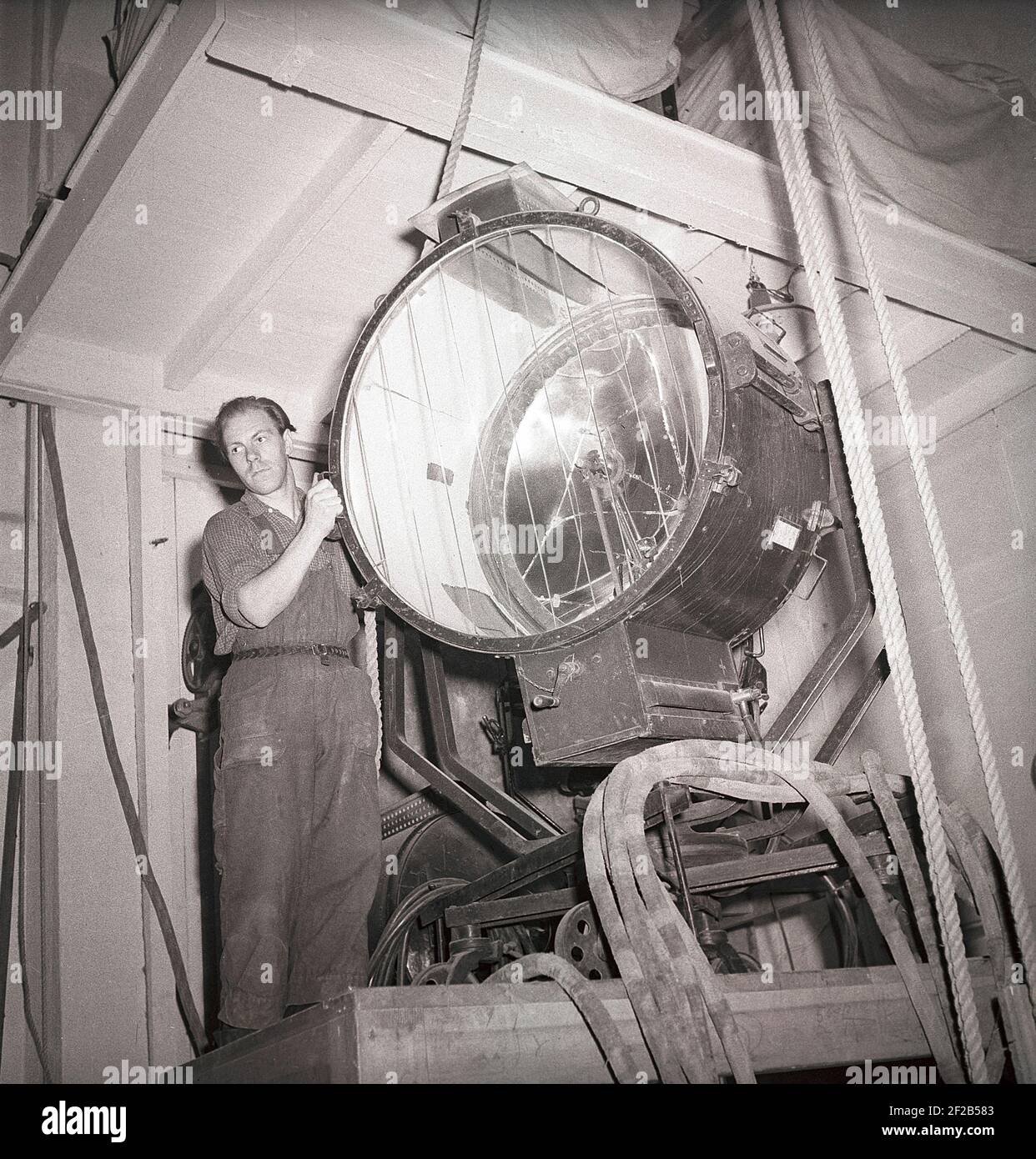 Filmstudio in der 1940s. Ein Mann, der an dem Filmset arbeitet, handhabt die riesige Lampe, mit der die Filmszene während der Aufnahme beleuchtet wird. Aufgenommen im größten Filmstudio in Schweden Filmstaden Råsunda während der Dreharbeiten von Ingmar Bergmans Film Frau ohne Gesicht. Es hatte Premiere september 16 1947. Schweden 1947. ref. AB5-10 Stockfoto