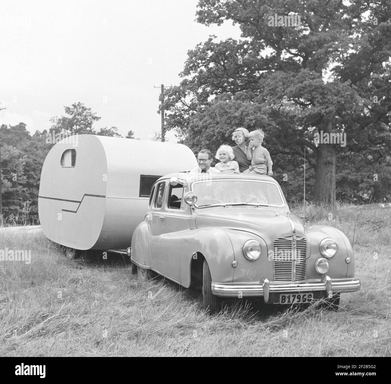 1950s Camping. Eine Familie im Auto und ein WohnwagenAnhänger bereit