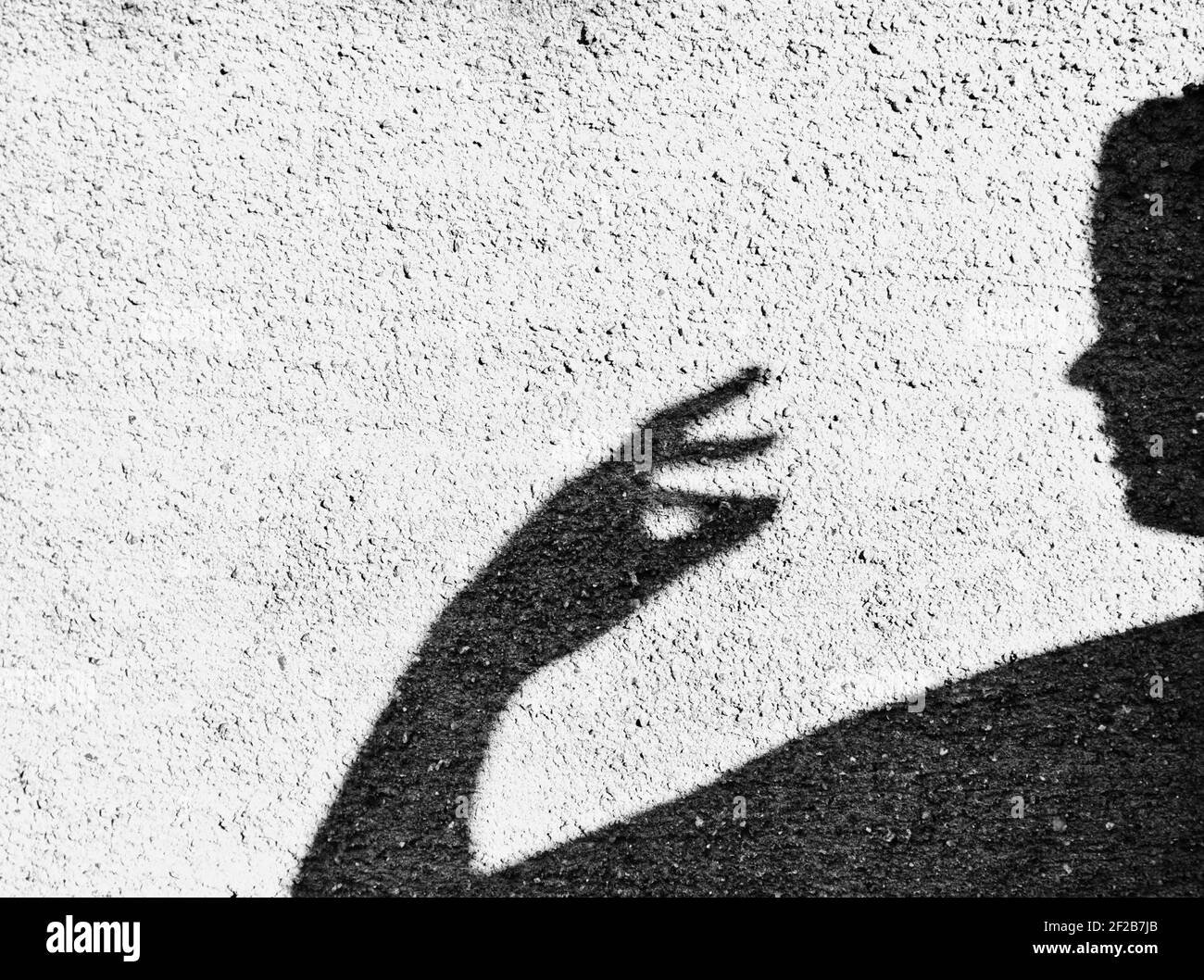 Schatten der weiblichen Statue mit erhobener Hand und Gesicht im Profil gegen strukturierte Wand. Konzept des Unerkennbaren, Verborgenen, Unbekannten Stockfoto
