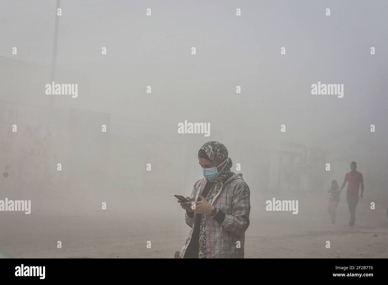 Obour City, Ägypten. März 2021, 11th. Eine Frau geht durch dichten Rauch, der durch das massive Feuer entsteht, das eine vierstöckige Bekleidungsfabrik in der Industriezone von Obour City, nördlich der ägyptischen Hauptstadt Kairo, getroffen hat, wobei mindestens 20 Menschen getötet wurden, während 24 weitere verletzt wurden. Bisher ist die Ursache des Feuern nicht klar. Kredit: Sayed Hassan/dpa/Alamy Live Nachrichten Stockfoto