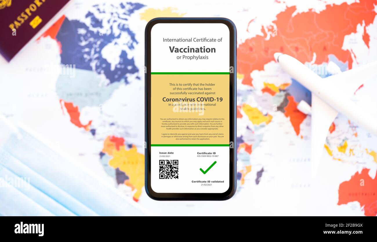Ein Smartphone mit Impfpass gegen den Covid-19 ist auf einer verschwommenen Weltkarte angeordnet. Stockfoto