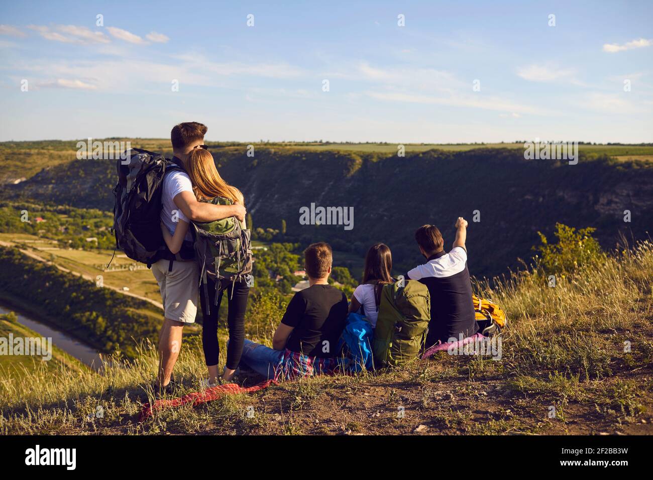 Junge Wanderer mit großen Rucksäcken beschlossen, vor dem Wandern in den Bergen zu stoppen, um sich auszuruhen. Stockfoto