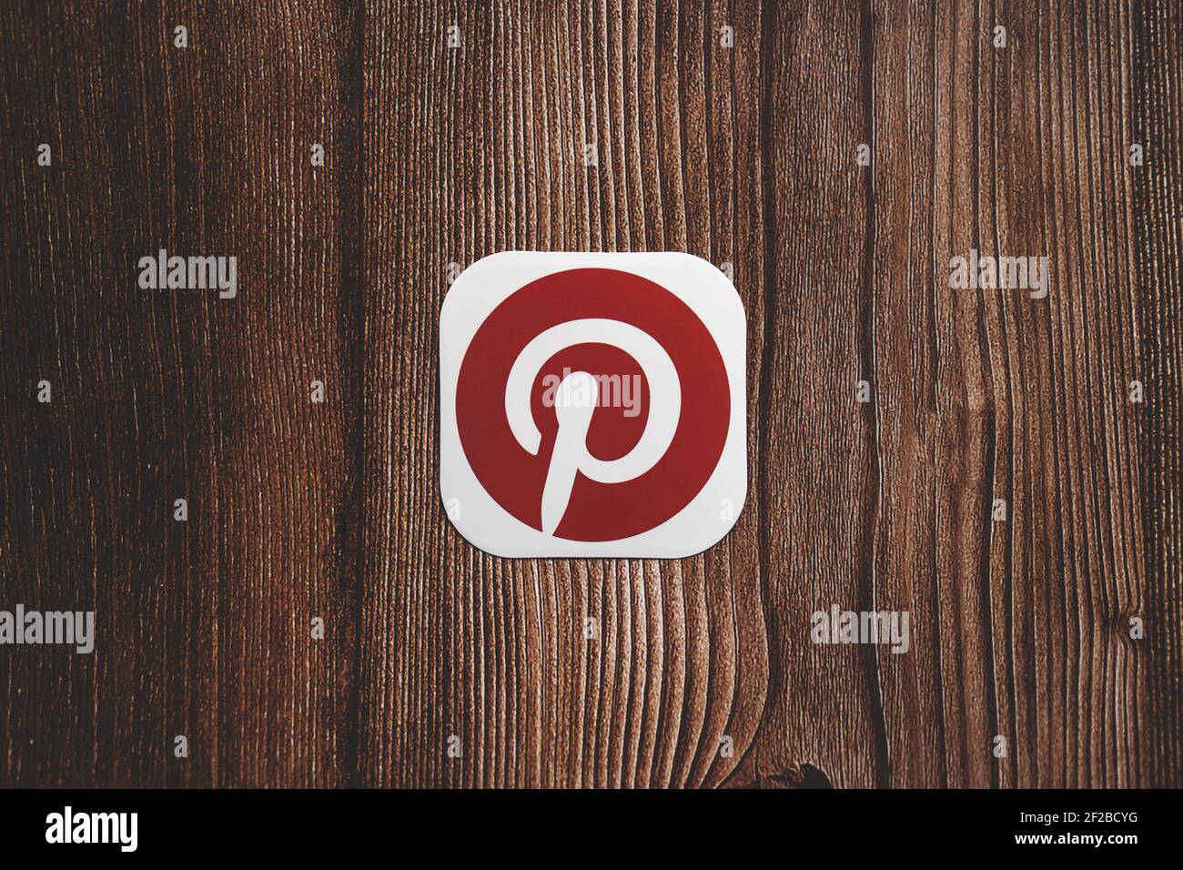 Pinterest rot rundes Logo auf Papier gedruckt mittig platziert auf Holzhintergrund Stockfoto