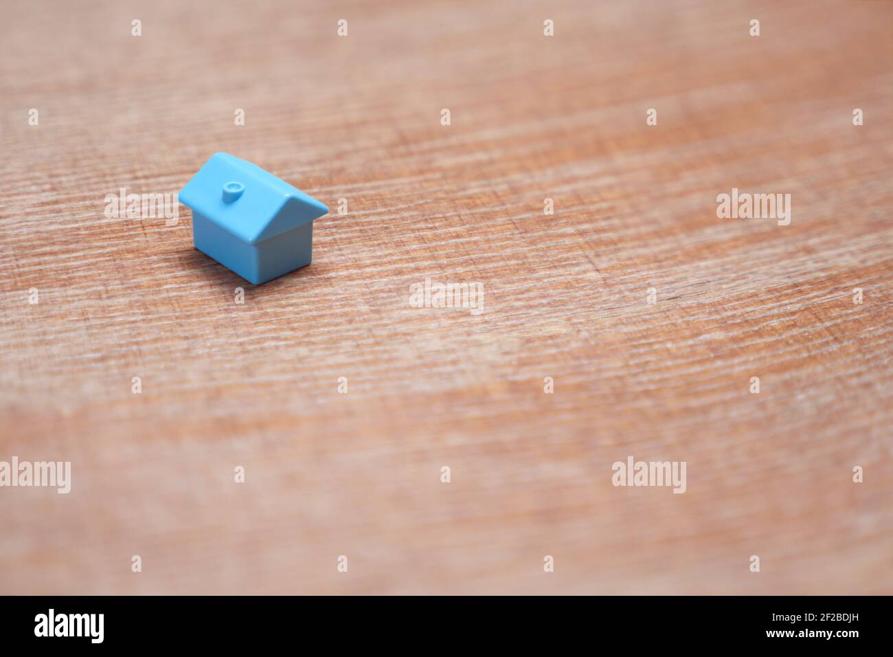 Minimalistisches Design ein einziges Miniaturhaus mit Kopierfläche. Blaues Spielzeug Haus Immobilienmarkt Gehäuse Hypothekendarlehen. Symbol des Hauses auf Holz Hintergrund Stockfoto