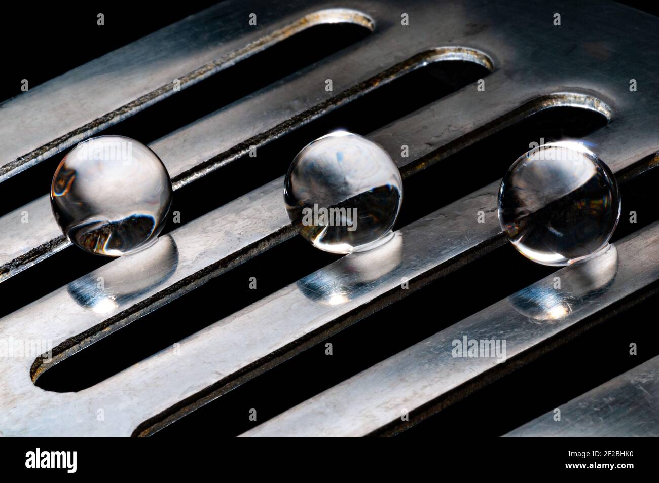 Drei Kristallkugeln in verschiedenen Schienen auf Inox-Stahl-Metall Unterstützung auf schwarzem Hintergrund Stockfoto