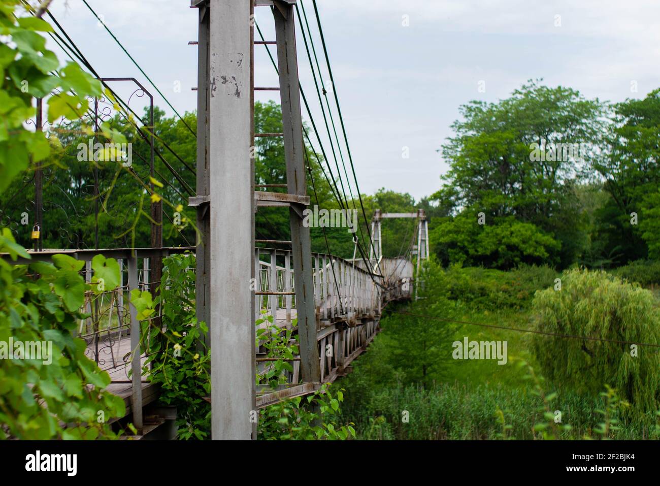 Alte eiserne Hängebrücke, die nicht funktioniert, über eine getrocknete Flussseite. Stockfoto