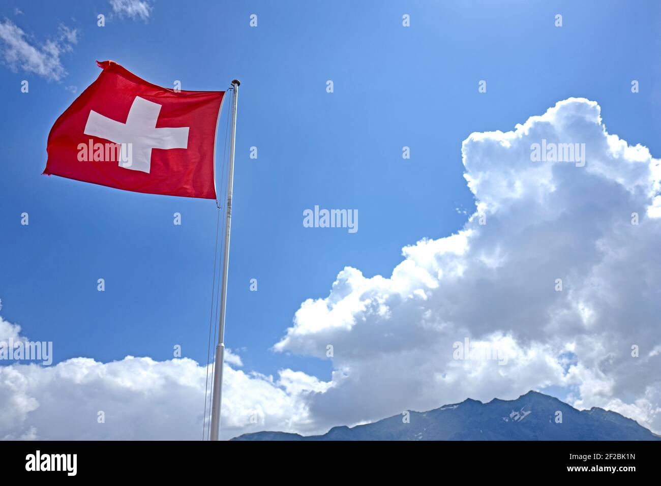 Schweizer Flagge winkt auf einer Berghütte mit den Alpen im Hintergrund. Stockfoto