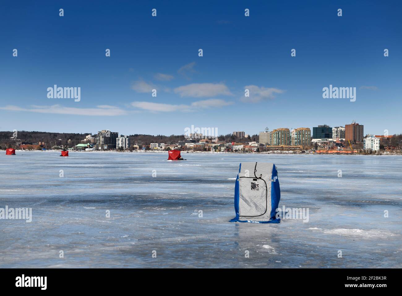 Barrie, Ontario, Kanada - 7. März 2021: Eisfischerhütten auf gefrorener Kempenfelt Bay of Lake Simcoe im Winter mit Stadtbild von Barrie Stockfoto