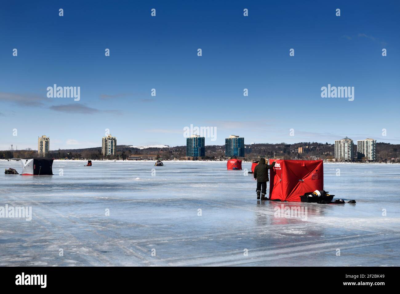 Barrie, Ontario, Kanada - 7. März 2021: Eisangelzelte auf gefrorener Kempenfelt Bay of Lake Simcoe im Winter mit Hochhauswohnungen von Barrie Stockfoto